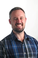 smiling person wearing a blue and black windowpane checked shirt