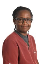 smiling person with short braids wearing spectacles and a red scrub top over a grey shirt