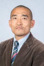 serious person wearing a brown sport coat over a light blue shirt and blue and red striped tie